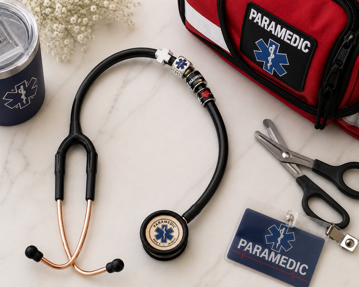 Personalized paramedic stethoscope charm on a black stethoscope with EMS gear, including a paramedic bag, trauma shears, and ID badge. Custom gift for paramedics, EMTs, and first responders.